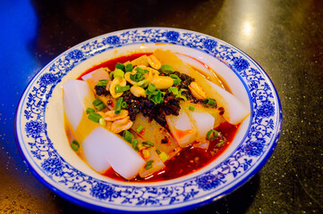 Chinese cold noodles garnished with black bean chili sauce, roast peanuts and chopped green spring onions.