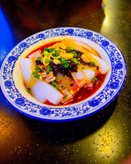Chinese cold noodles garnished with black bean chili sauce, roast peanuts and chopped green spring onions.