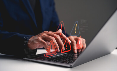 A person types on a laptop, surrounded by digital warning symbols, suggesting cybersecurity concerns or technical issues.