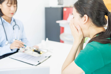 Obraz premium A woman is handing a tray of medical supplies to another woman. The tray contains a pen, a bottle, and a pair of scissors. The scene suggests a medical setting 