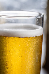 Cold light beer with foam and condensation close-up