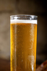 Cold light beer in tall glass with foam