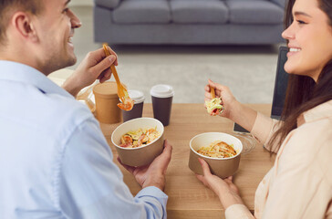 Happy family couple is eating a takeaway meal or delivery food, indulging in a delicious wok at...