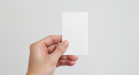 Fototapeta premium A hand holding a blank white card for mockup, presentation, and design purposes.