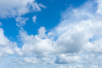 Bright blue sky filled with fluffy white cumulus clouds and wispy cirrus formations