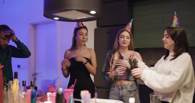 Friends Celebrate a Birthday Together in a Festive Kitchen with Party Hats, Balloons, and Colorful Decorations