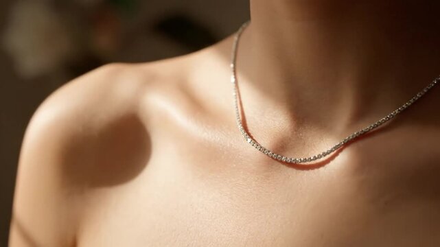 Close up of a woman's shoulder and collarbone with a delicate silver necklace