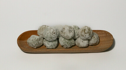 Mochi, a sweet dessert or rice cake filled with chocolate or mung beans, and coated with sesame seeds Mochi cake on a plate with a white background.