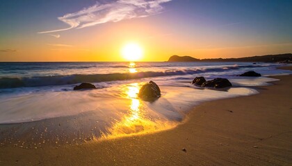 Golden sunset over ocean waves crashing on sandy shore, with rocks in view