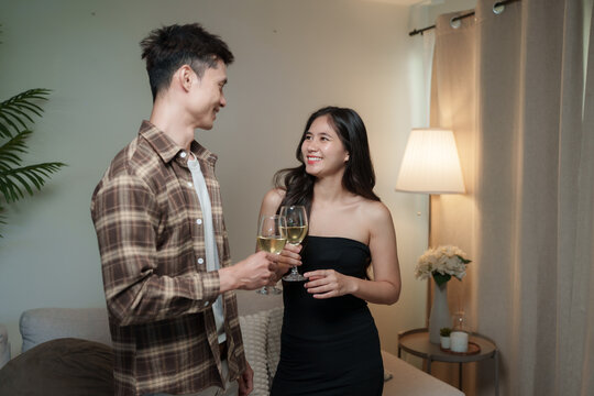 Young couple cheering with wine glasses at home