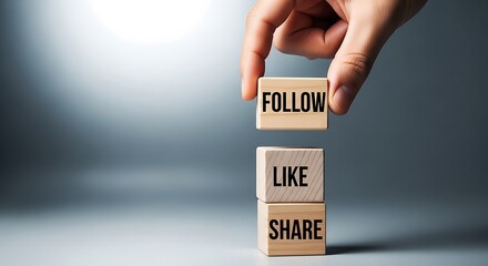Hand stacking wooden blocks with the words follow, like, and share, representing social media engagement