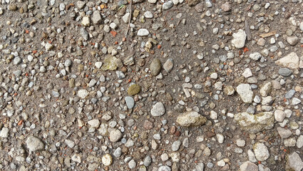Natural sand and small pebble texture background. Fine gravel and tiny stones mixed on dry surface. Perfect for design, wall, or ground pattern use in nature, beach, and construction themes.