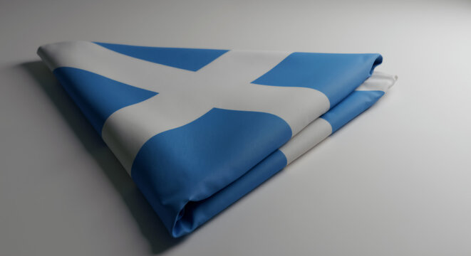 The national flag of Scotland folded into a triangle on a plain background. Close-up of the Scottish Saltire, a symbol of patriotism and identity. St. Andrew's Day concept with copy space