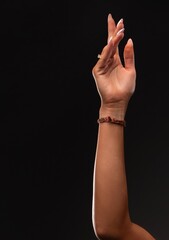 Woman's arm extended with delicate hand gesture on black background