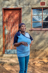 african woman in the village, standing in front of the house, rural life in Botswana