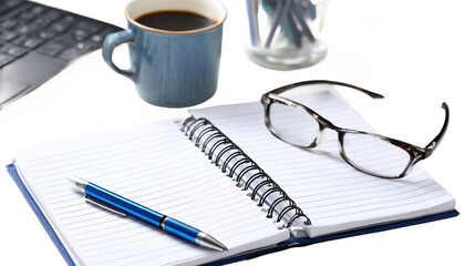 Coffee, notebook, and glasses on a desk.