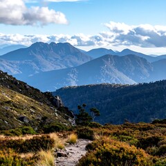 Fototapeta premium Layered mountain ranges with a hiking trail under a partly cloudy sky