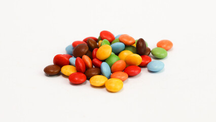 Colorful candy coated chocolate gems forming a vibrant border on white background