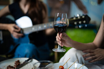 Multiethnic group of friends having a backyard dinner party. Happy friends clinking glasses of Cabernet Sauvignon. Focus on wine glasses. Alcohol lifestyle concept.