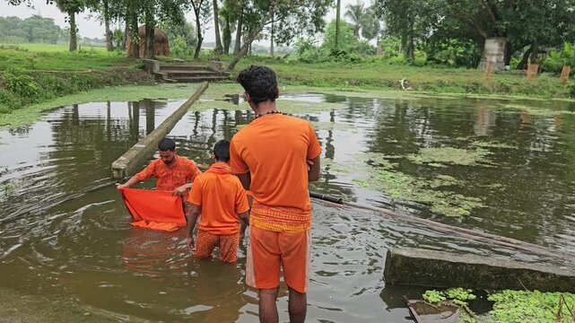 Authentic footage of Kanwariya devotees dressed in saffron clothing collecting holy water from a village pond during the sacred Shravan Somwar Sawan Monday pilgrimage in India.