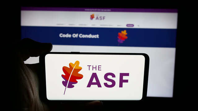 Stuttgart, Germany - 10-08-2025: Person holding cellphone with logo of organisation Apache Software Foundation (ASF) on screen in front of webpage. Focus on phone display.