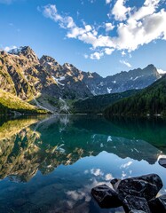 Serene lake reflecting mountains and clouds on a bright sunny day