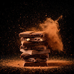 Stacked chocolate bars with cocoa powder explosion