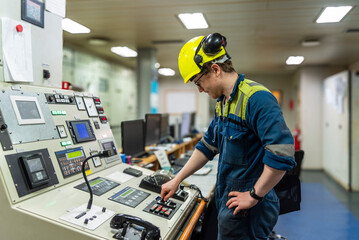 Young marine engineer during his daily routine work in engine room. Seafarers life.