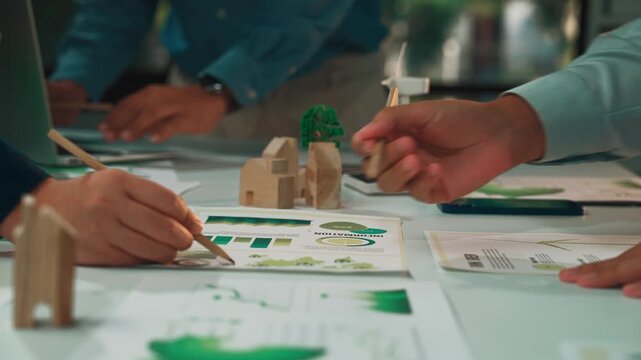A collaborative team works on an eco-friendly project in a modern office, analyzing data and discussing innovative ideas using charts and sustainable models. SACTR