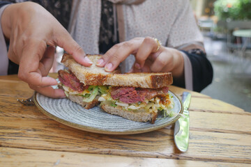 Hands preparing a delicious sandwich at a cafe table