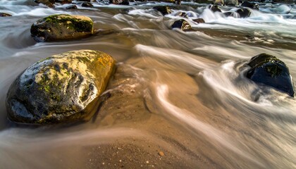 Smooth river water flows around river stones, creating motion blur