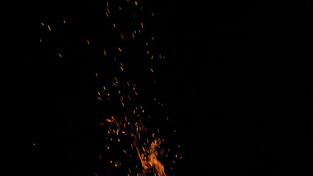 sparks and embers from campfire flying over black background
