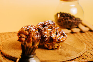 Freshly baked cinnamon rolls on a wooden board beside coffee beans