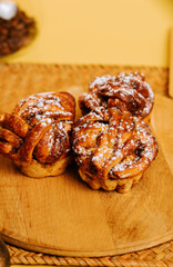 Warm cinnamon rolls with powdered sugar on a wooden board in a cozy kitchen setting