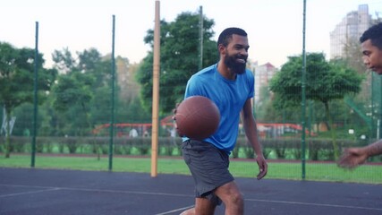 Side view of sporty African American man basketball player driving to hoop, scoring two points with layup shot after assist from teammate while multi ethnic athletes playing streetball game on court
