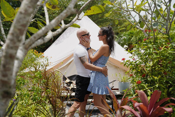 A couple of man and woman in front of a tent at glamping.