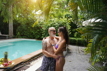 A man and a woman joyfully walking in front of a beautiful pool