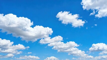 Fototapeta premium Bright white cumulus clouds float across a clear blue sky.