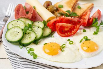 English breakfast - fried egg, salami, cheese, tomatoes, cucumbers and toast.