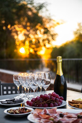 Aperitivo setup with wine glasses champagne bottle and assorted snacks at sunset