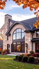 Stone house with arched windows, autumn leaves, manicured lawn