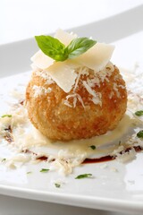 Delicious arancini ball plated with parmesan cheese and fresh basil on a white plate a gourmet appetizer perfect for fine dining experiences