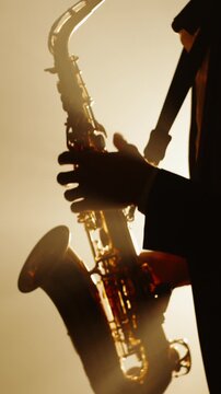 vertical slow motion silhouette of saxophonist performing on stage in warm light and smoke symbol of art of sound creative soul retro jazz night vintage mood and artistic inspiration
