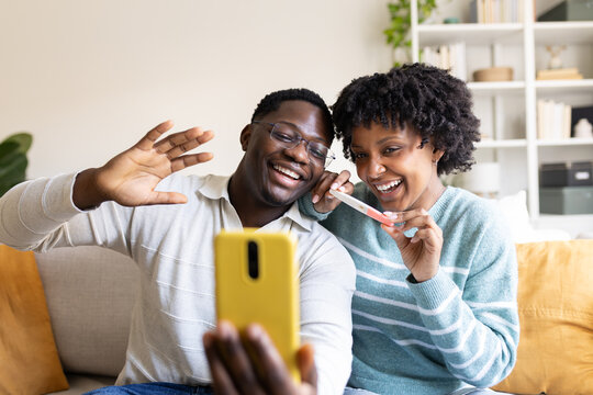 Happy couple sharing pregnancy test result on video call