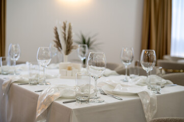 A sophisticated restaurant table arranged with white linens, crystal glassware, polished cutlery, and a delicate floral centerpiece. Plush seating and ambient lighting create an inviting, upscale
