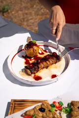 Close-up of an elegant restaurant dish with sliced duck breast topped with berry sauce, served with baked apple and fresh garnish on a white plate fine dining presentation.