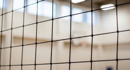 Indoor sports gymnasium with volleyball net and basketball hoop