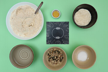 Ingredients for bread preparation on green background with label mockup. Minimal baking concept for organic and homemade food.
