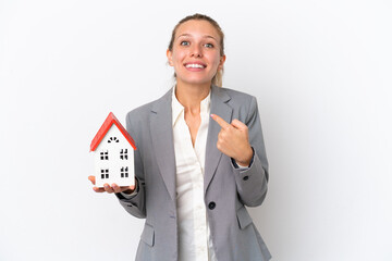 Real estate agent woman holding a toy house isolated on white background with surprise facial expression