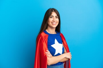 Super Hero caucasian woman isolated on blue background with arms crossed and happy © luismolinero